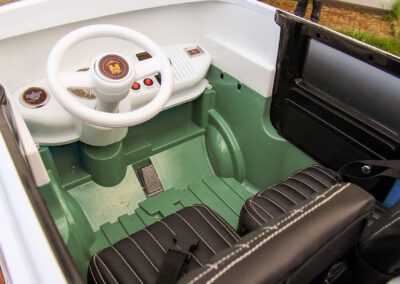 Kinderbulli als Elektroauto Innenraum mit Doppelsitzen schwarzes Leder und Gurten und abgesetzten Nähten Lackierung lindgrün Lenkrad weiß Gaspedal