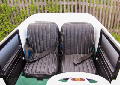 Kinderbulli als Elektroauto Innenraum mit Doppelsitzen schwarzes Leder und Gurten und abgesetzten Nähten