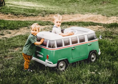 Kinderbulli mit zwei kleinen Jungen mit elektrischem Antrieb in lindgrün auf der Wiese T1 Bulli